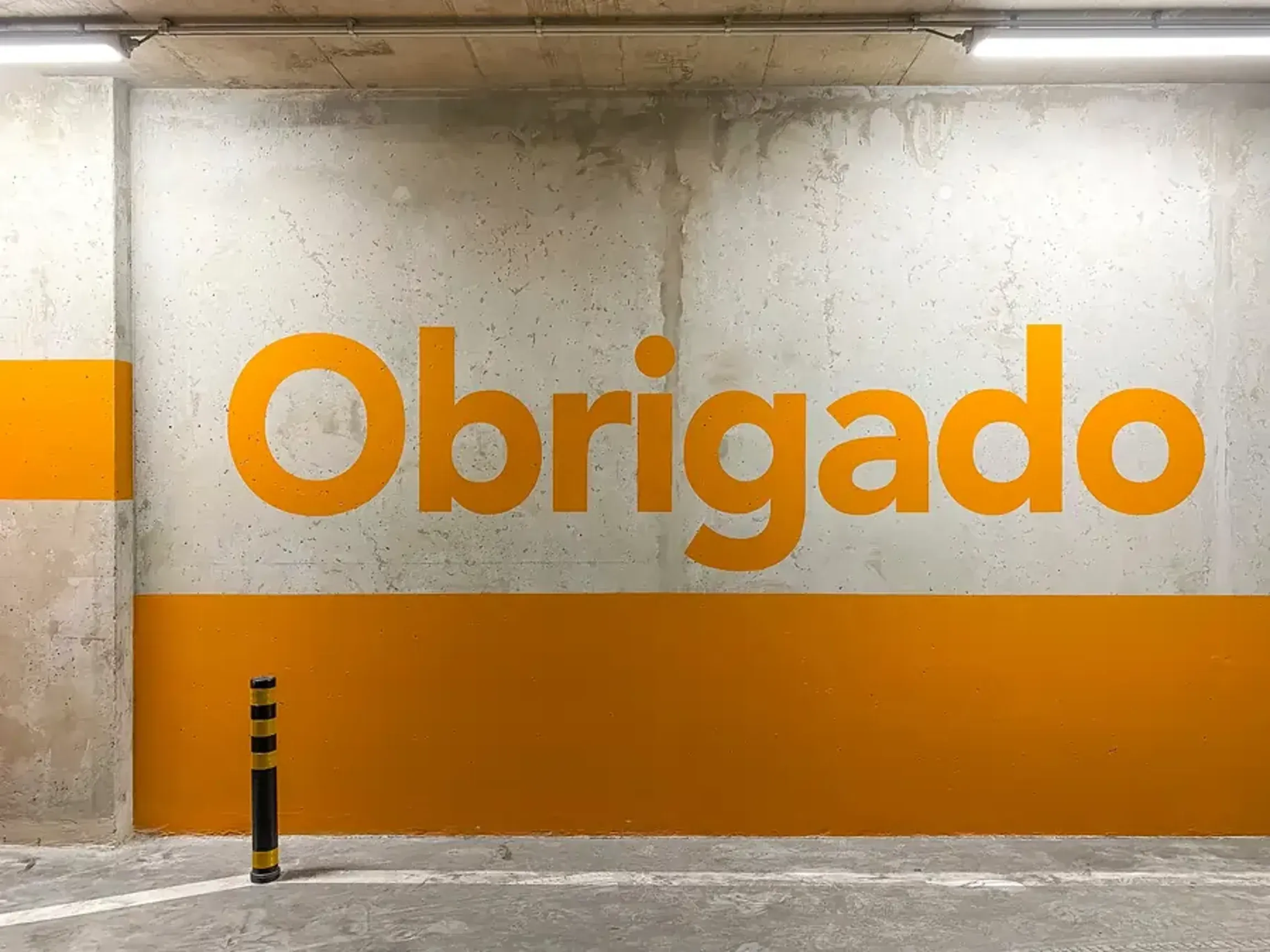 Concrete wall with large orange “Obrigado” text.